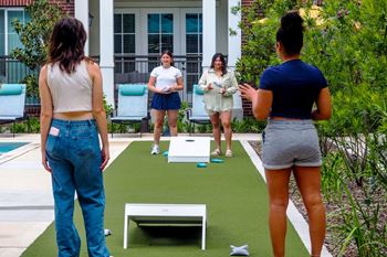 Three women playing a game on a green artificial lawn.